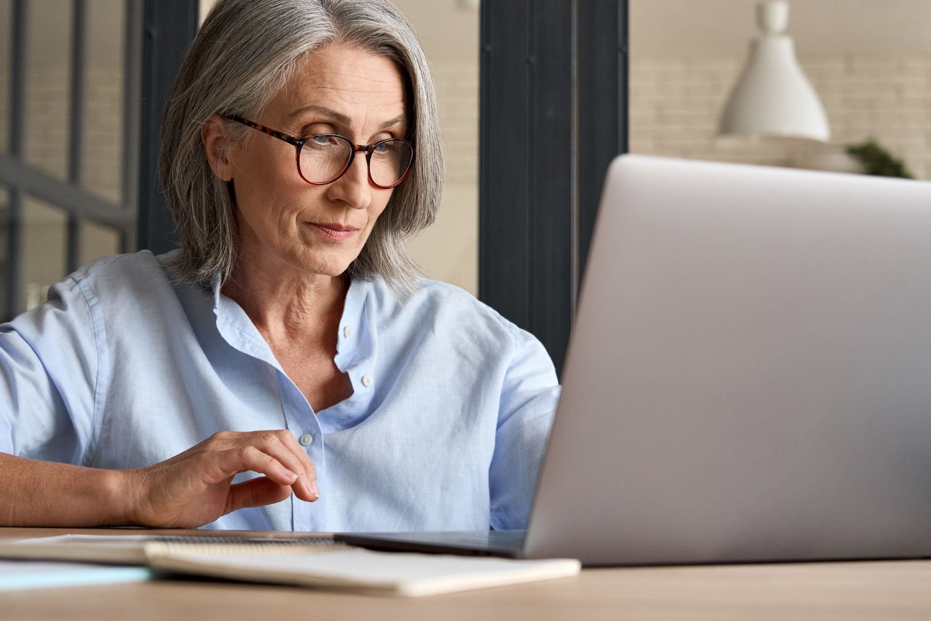 Femme senior devant un ordinateur : qui prévenir en cas de décès d'un retraité ?